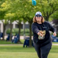 A participant throws a bag during a game wearing a hat and sunglasses